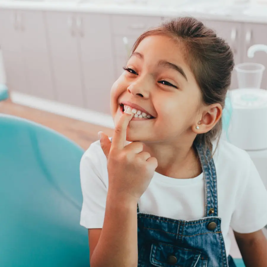 A child patient Showing Her Perfect Toothy Smile While Sitting Dentists Chair