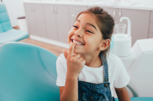 A child patient Showing Her Perfect Toothy Smile While Sitting Dentists Chair